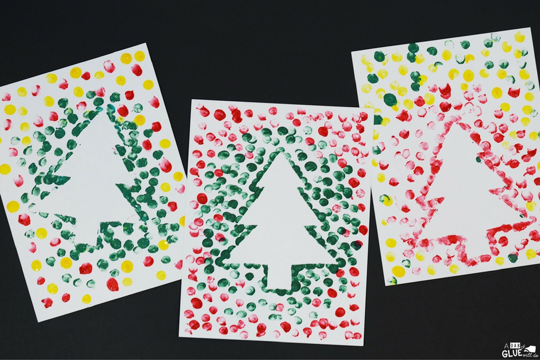 white christmas outline on a piece of paper surrounded by green and red fingerprints 