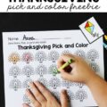 A paper with small turkeys that have the letters of the alphabet on them. A card with a kite and a child's hands coloring in the turkey with the "K" on it with a green crayon.