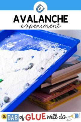 A plastic blue tray full with flour and manipulatives tilted up on a pile of books