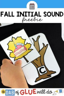 A paper tree with the letter c on it with a child holding a leaf card with a picture of cake on it.