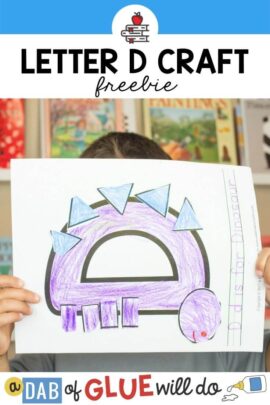 A child holding up a D is for dinosaur letter craft
