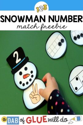 A child adding a snow ball with the number 2 showing on fingers to a snowman puzzle that has the number two on the top hat of the snowman.